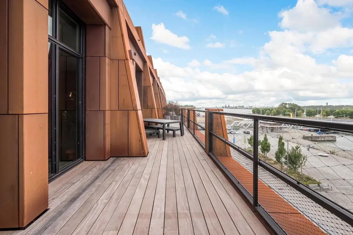 Immeuble moderne à façade en acier rouille donnant sur une place pavée